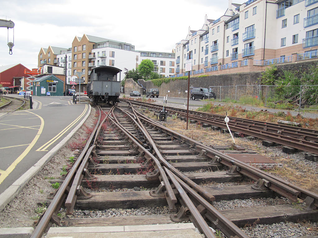 Railway tracks converging into one switch near a row of apartment buildings